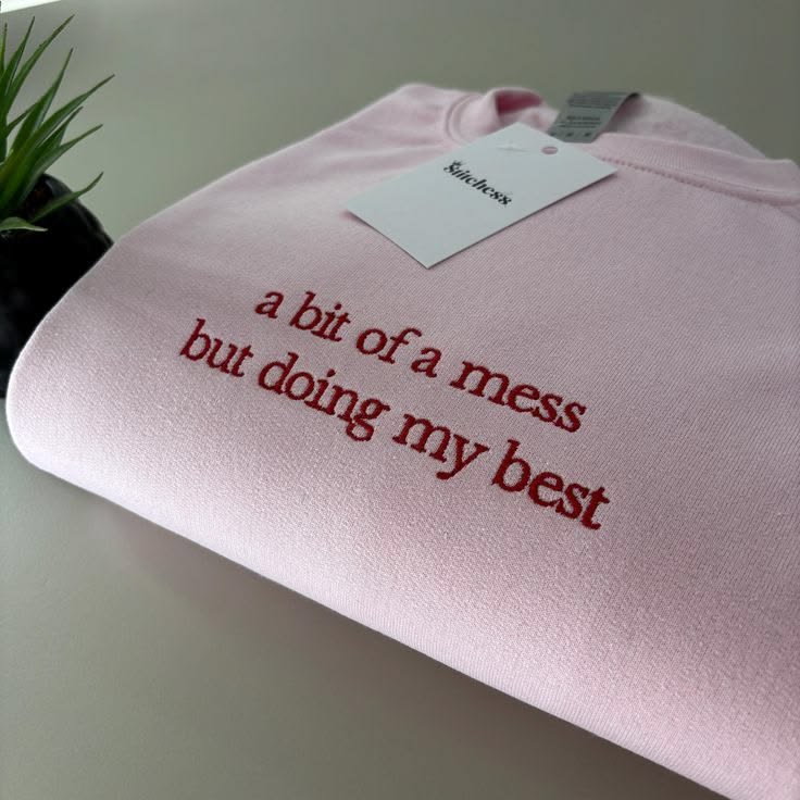 Folded pink sweatshirt with a two-line embroidered quote — Pinterest inspiration