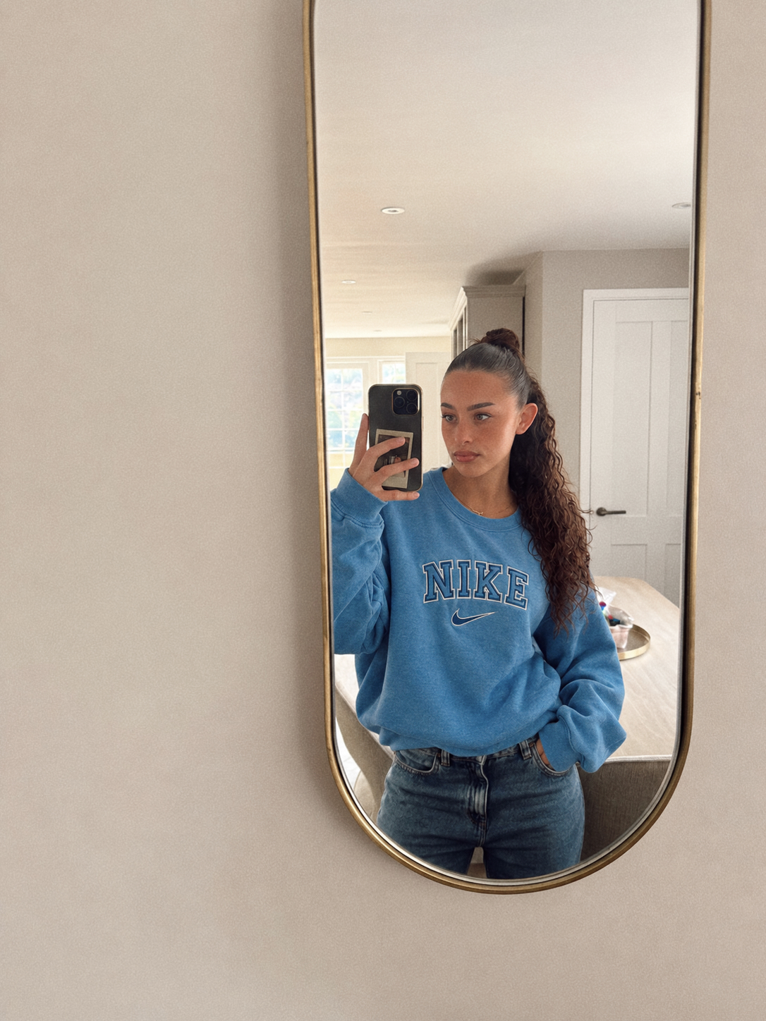 Blue embroidered crewneck worn with jeans in a mirror photo