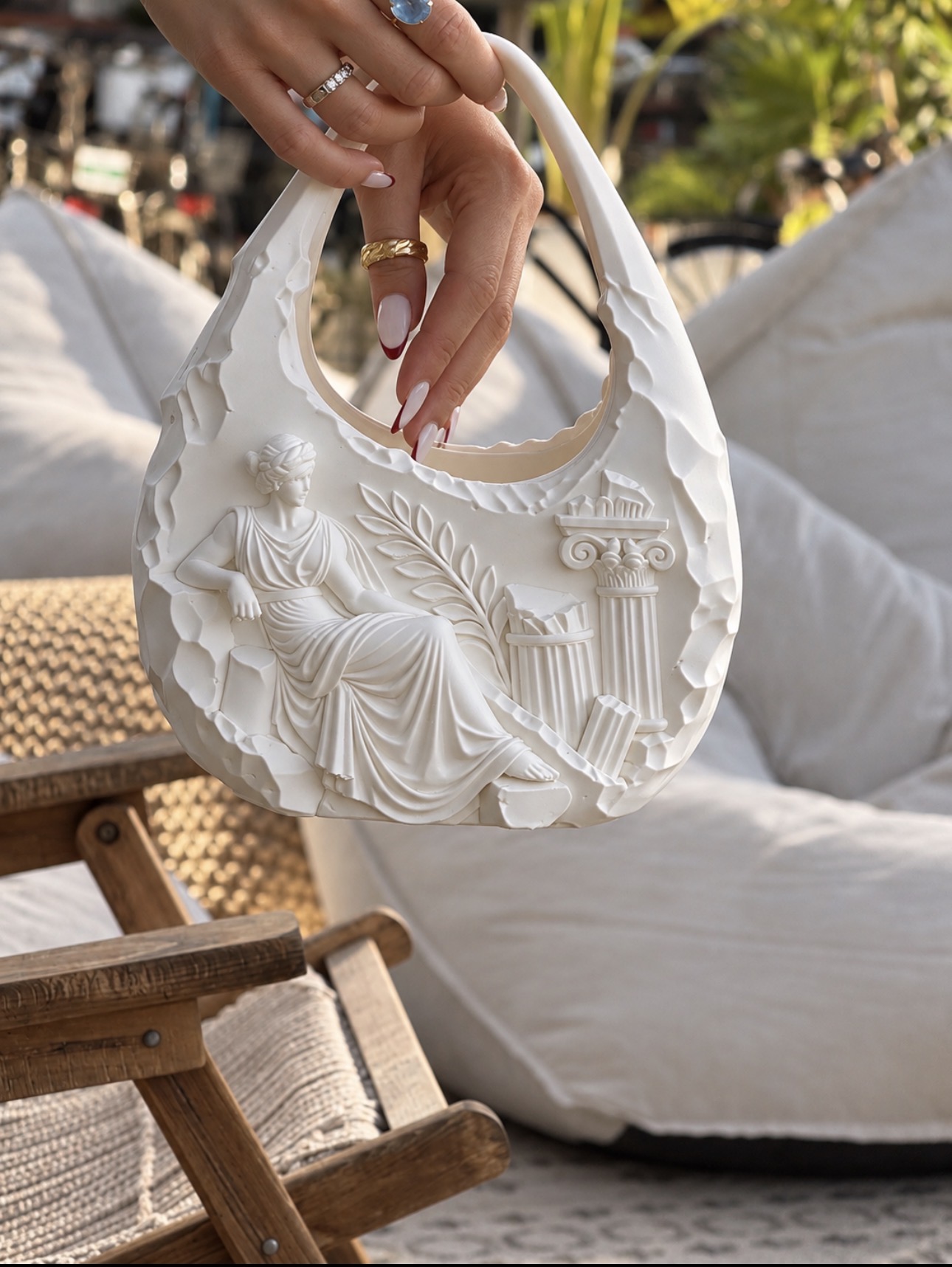 White sculptural bag with classical figure and columns, held by its handle