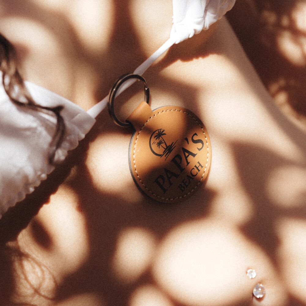 Tan leather AirTag key chain with laser-engraved PAPAS Beach logo