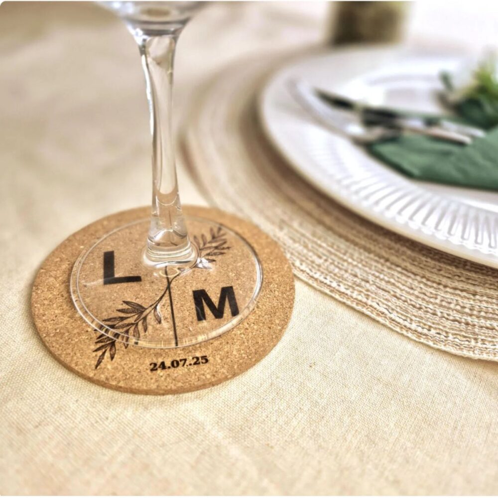 Engraved cork wedding coaster with initials and date beneath a wine glass