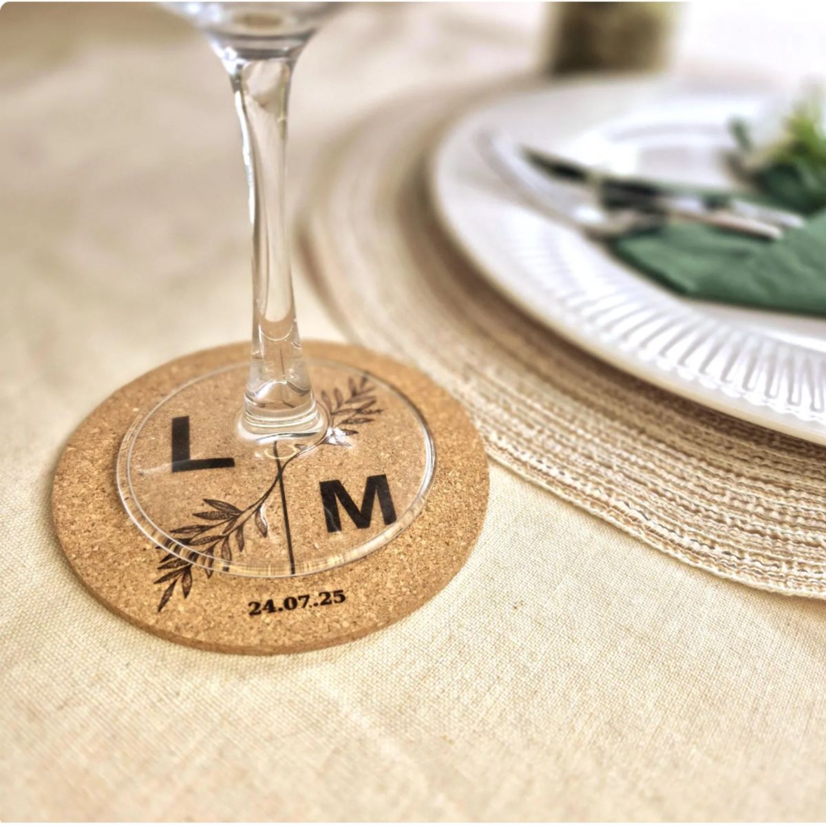 Engraved cork wedding coaster with initials and date beneath a wine glass