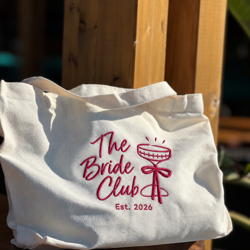 Cream Event Tote with raspberry embroidered The Bride Club design, champagne coupe and bow